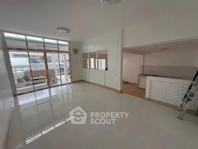 Spacious open-plan living room with large windows and modern kitchen area.