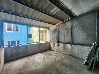 Spacious covered balcony with metal mesh walls and concrete flooring, ideal for outdoor activities.