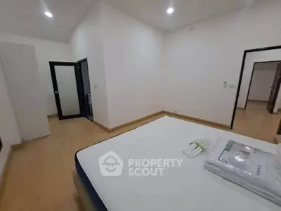 Spacious bedroom with modern design and ample natural light, featuring a comfortable bed and sleek flooring.