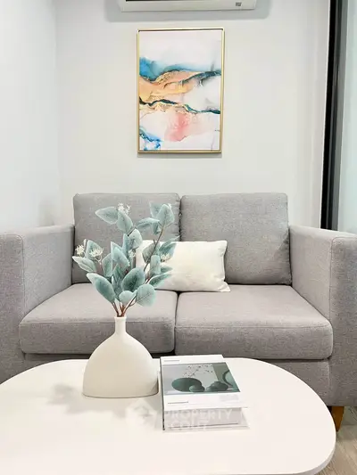 Modern living room with stylish gray sofa and abstract art, perfect for cozy relaxation.