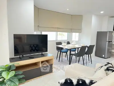 Modern living room with dining area and TV, featuring stylish decor and natural light.