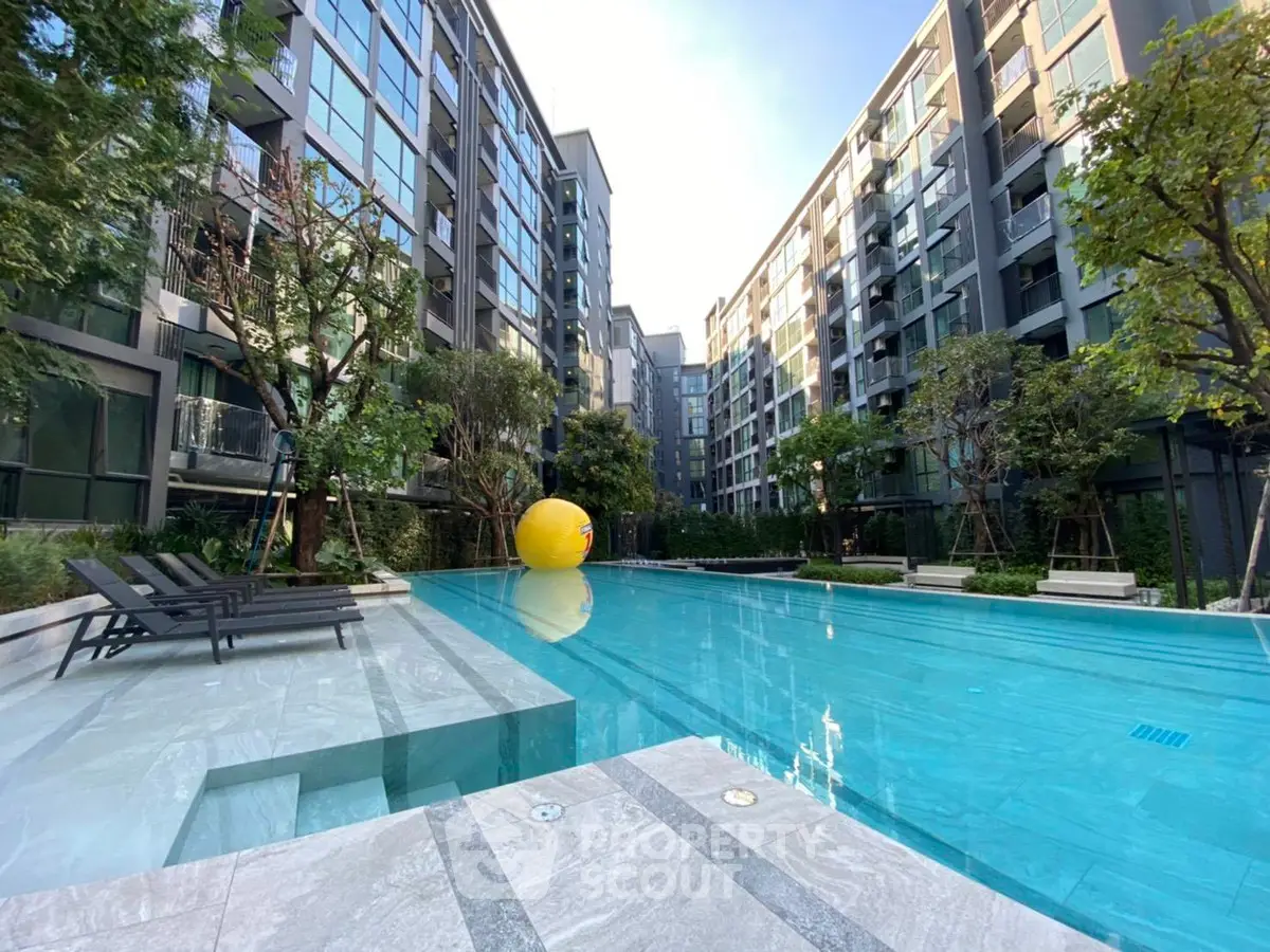Luxurious modern apartment complex with a stunning outdoor pool and lush greenery.