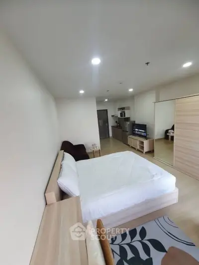 Modern studio apartment with cozy bedroom and compact kitchen area.