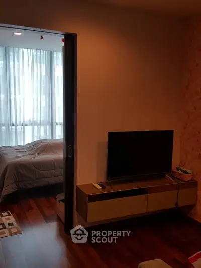 Cozy bedroom with TV and wooden flooring in modern apartment