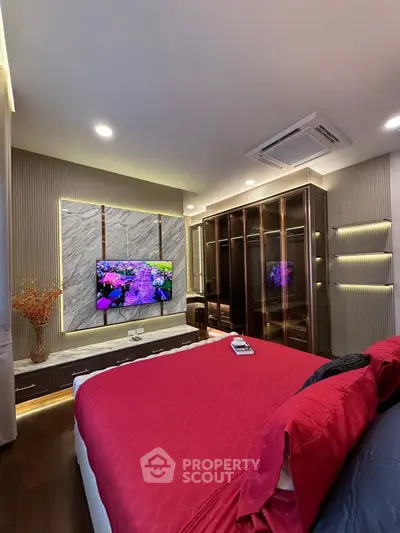 Luxurious bedroom with modern decor, featuring a large TV and elegant lighting.