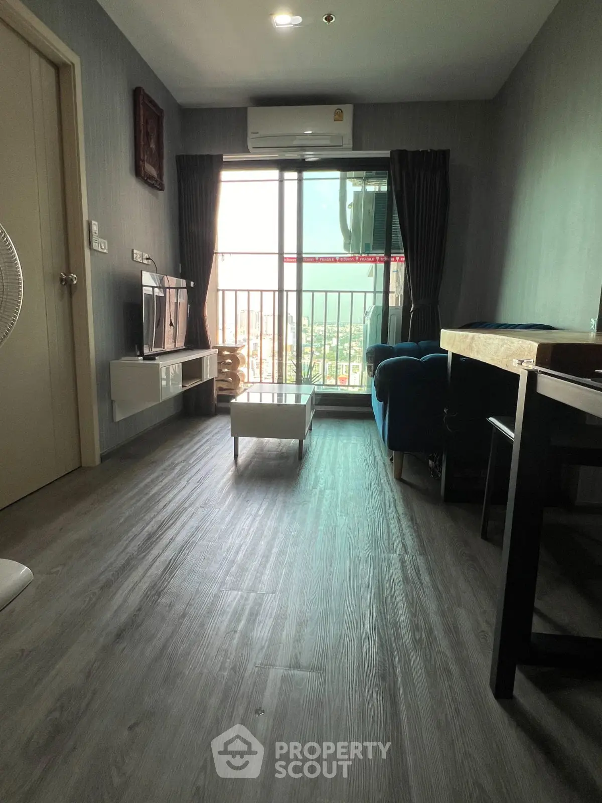 Modern living room with balcony view, stylish decor, and abundant natural light.