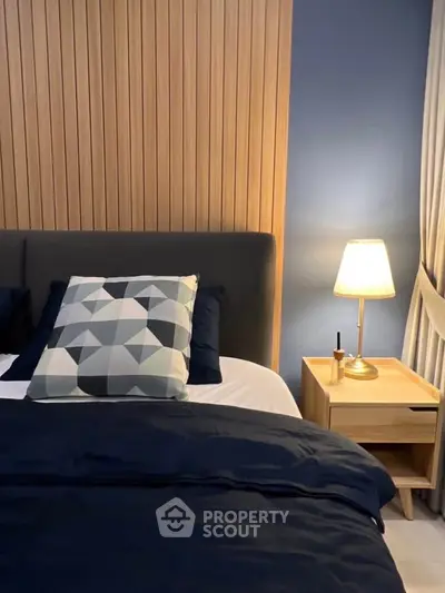 Cozy bedroom with modern decor, featuring a stylish geometric pillow and warm lighting.