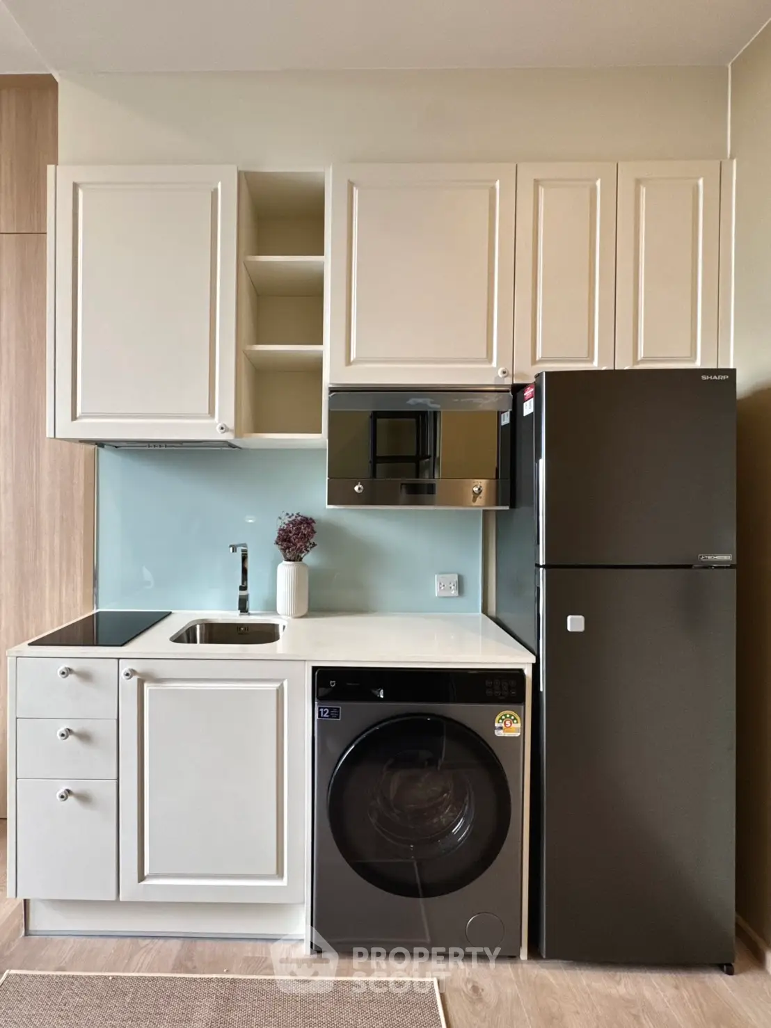 Modern compact kitchen with washing machine and fridge in sleek design.