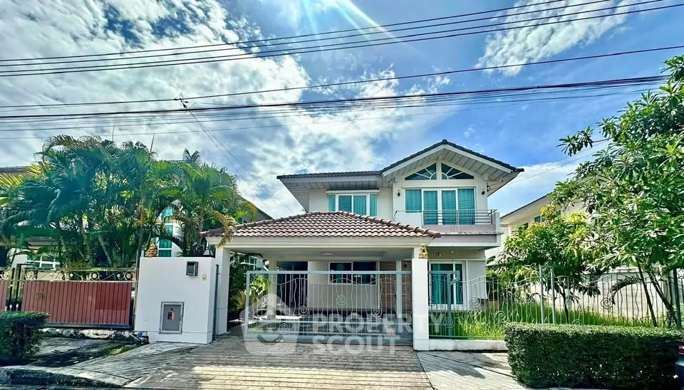 Charming two-story house with lush garden and spacious driveway under a bright blue sky.