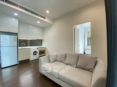 Modern living room with sleek kitchen and cozy sofa in open layout apartment.