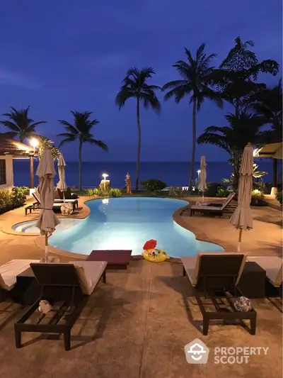 Luxurious beachfront pool with palm trees and ocean view at sunset