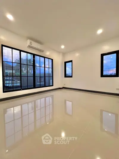 Spacious modern living room with large windows and glossy tiled floors
