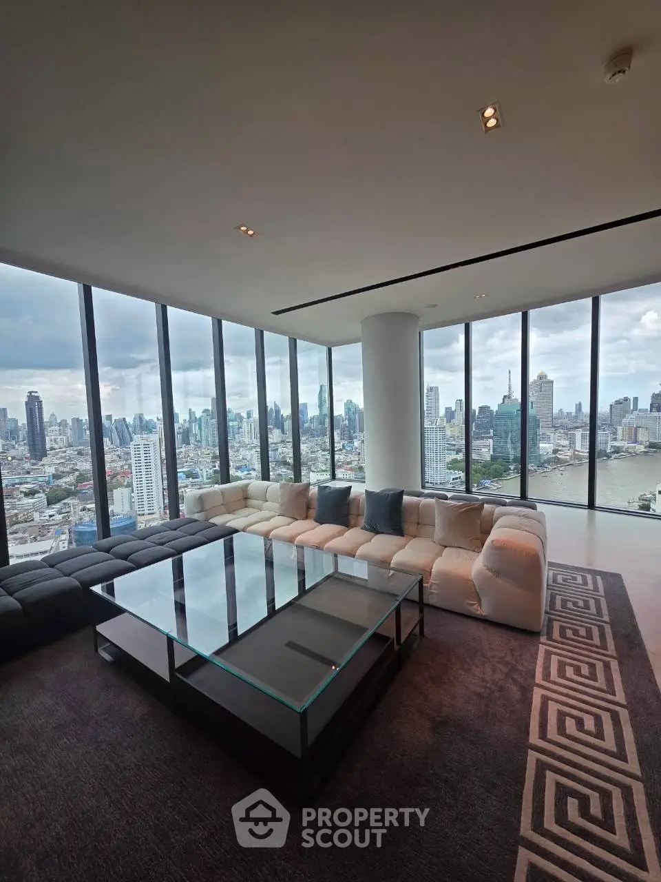 Luxurious corner unit living room with panoramic city skyline views and modern furnishings.