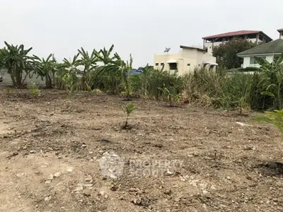Vacant land plot with potential for development in a suburban area, surrounded by greenery and nearby houses.