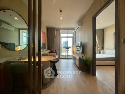 Modern apartment interior with open living room and bedroom, featuring stylish decor and balcony view.