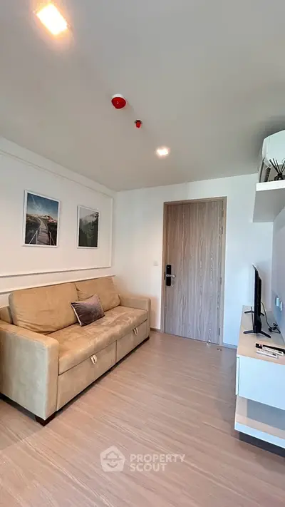 Modern living room with beige sofa and wall-mounted TV in a stylish apartment.