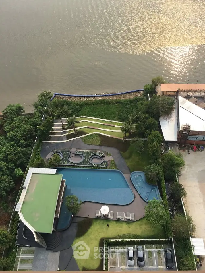 Stunning aerial view of riverside property with luxurious pool and lush greenery, perfect for serene living.