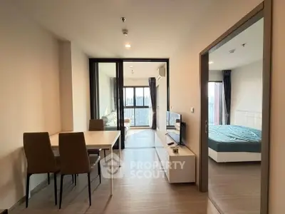 Modern apartment interior with open living room and bedroom, featuring sleek furniture and city view.