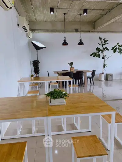 Modern co-working space with minimalist design and natural light, featuring wooden tables and stylish lighting.