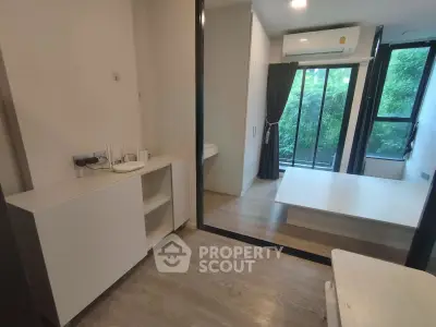 Modern apartment interior with large windows and wooden flooring, featuring a compact living space and air conditioning.