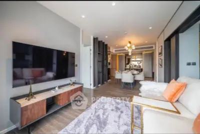 Modern living room with stylish decor and open layout, featuring a large TV and elegant dining area.