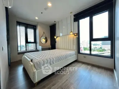 Modern bedroom with large windows and city view, featuring stylish decor and natural light.