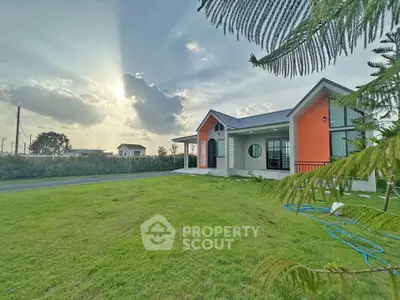 Charming modern house with vibrant exterior and lush green lawn under a stunning sunset sky.