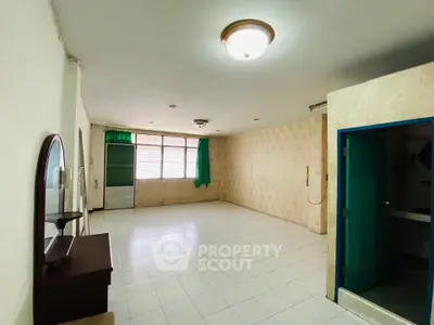 Spacious room with tiled flooring and large window, ideal for versatile living space.