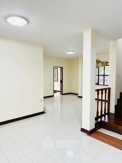 Spacious open-plan living area with bright natural light and elegant staircase.