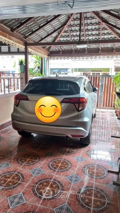 Covered parking area with tiled floor and parked car in residential property.