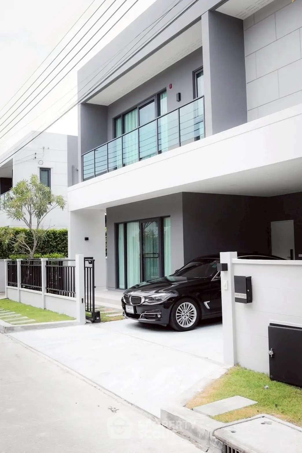 Modern two-story house with sleek design and luxury car parked in driveway, showcasing contemporary architecture.