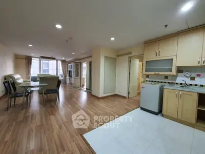 Spacious open-plan living room and kitchen with wooden flooring and modern furnishings.