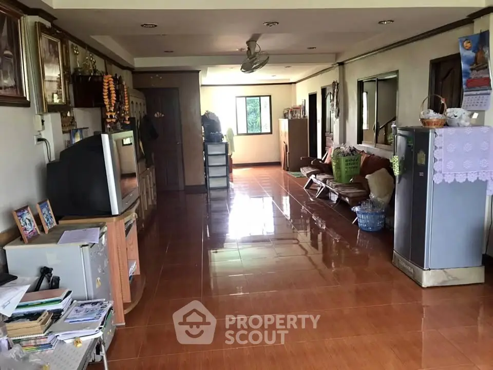 Spacious living room with tiled flooring and ample natural light, featuring a cozy seating area and traditional decor.