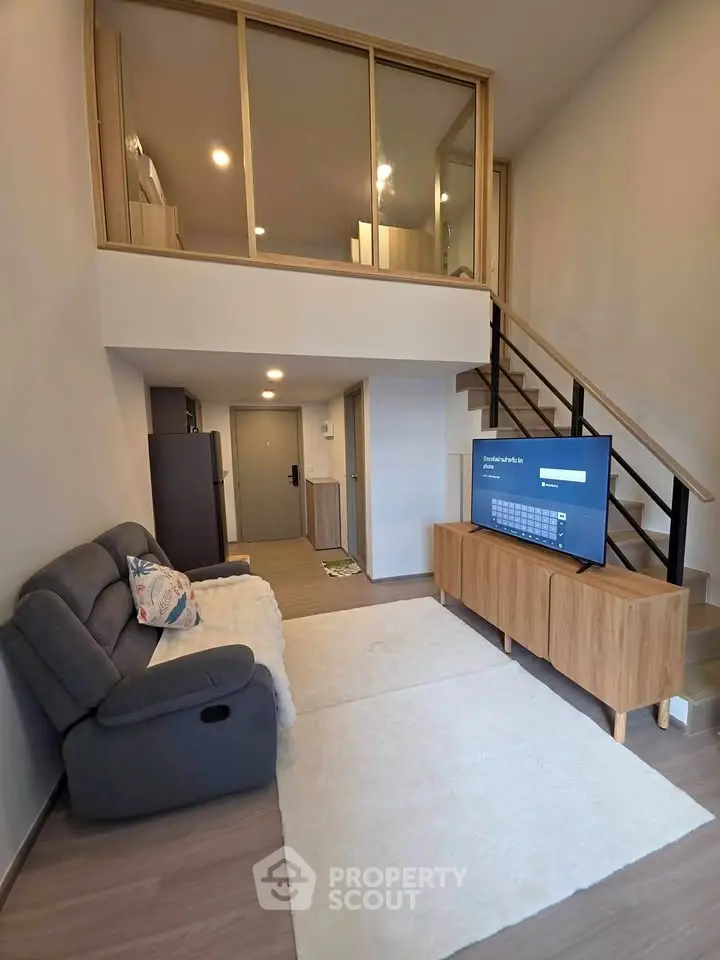 Modern loft-style living room with cozy seating and sleek wooden staircase