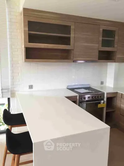 Modern kitchen with sleek white countertops, wooden cabinetry, and stainless steel appliances, perfect for culinary enthusiasts.