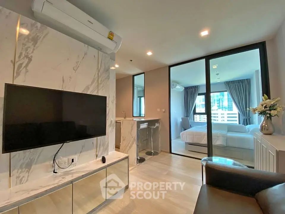 Modern living room with TV and view into stylish bedroom