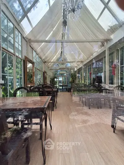 Stunning glass-walled conservatory with elegant dining setup and lush garden views.
