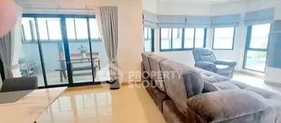 Spacious living room with plush seating and large windows offering natural light and a view.