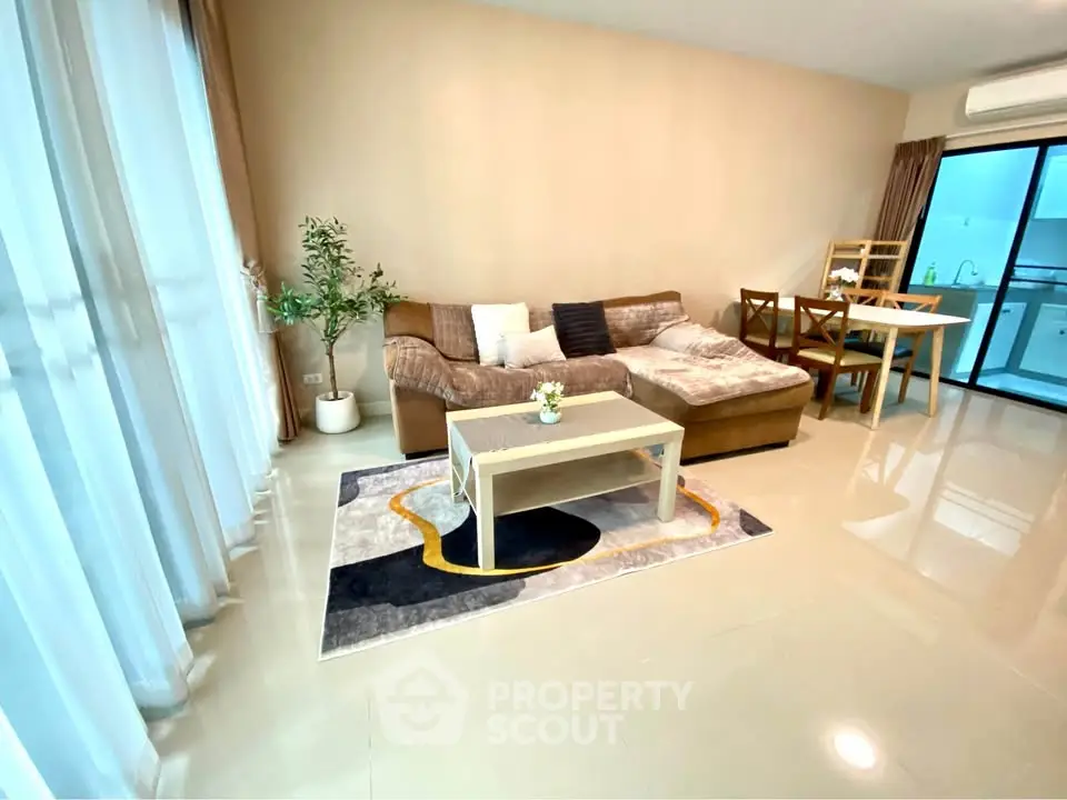 Spacious living room with cozy sofa and dining area, adjacent to modern kitchen.