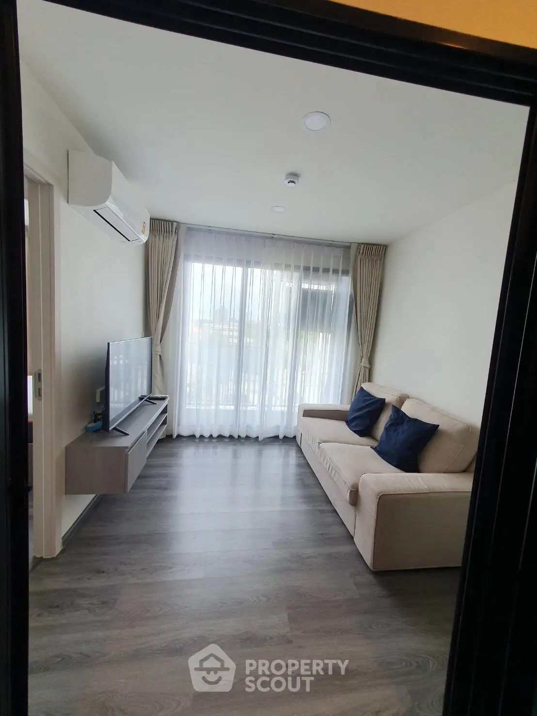 Modern living room with sleek flooring, cozy sofa, and large window for natural light.