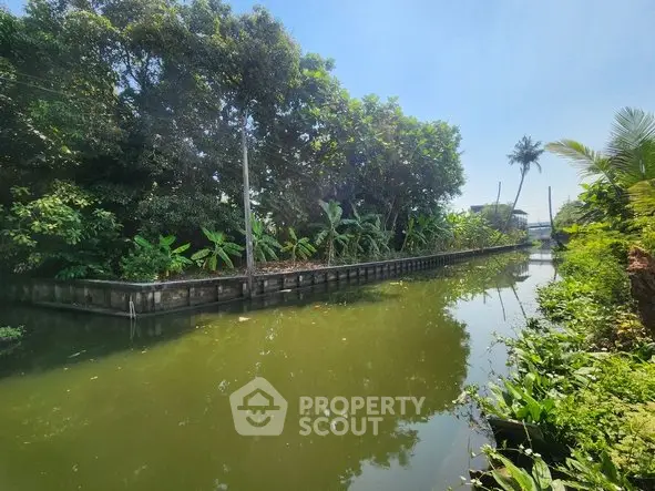 Scenic canal view with lush greenery and clear blue sky, perfect for serene waterfront living.