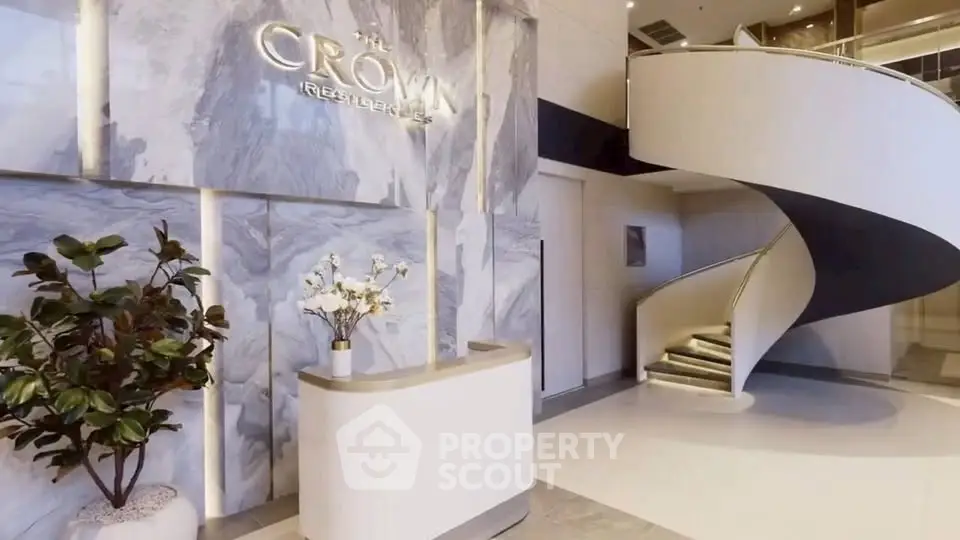 Luxurious lobby with elegant spiral staircase and modern decor at The Crown Residences.
