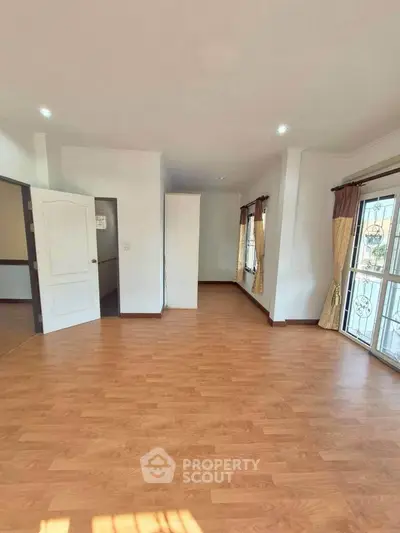 Spacious interior with wooden flooring and large windows, perfect for natural light.