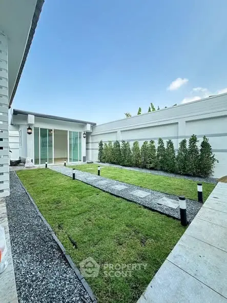 Modern home exterior with lush green lawn and sleek pathway