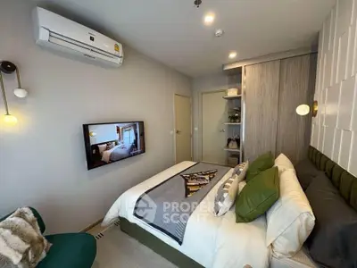 Modern bedroom with stylish decor and wall-mounted TV, featuring air conditioning and cozy bedding.