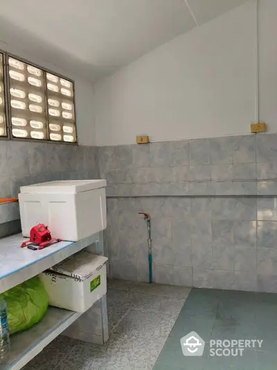 Spacious tiled utility room with shelving and natural light