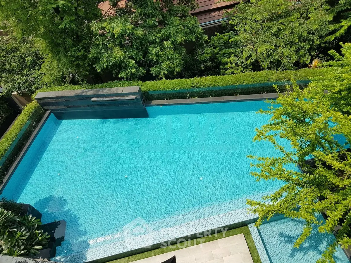 Luxurious outdoor swimming pool surrounded by lush greenery, perfect for relaxation and leisure.