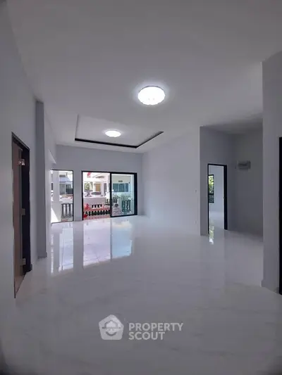 Spacious modern living room with large windows and glossy white flooring