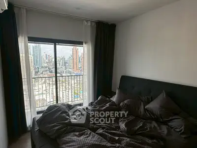 Cozy bedroom with city view from high-rise apartment, featuring a comfortable bed and large window.
