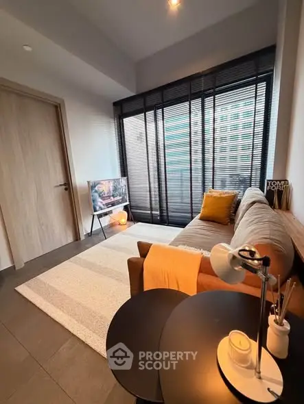 Modern living room with stylish decor, cozy sofa, and large window with blinds, perfect for relaxation.